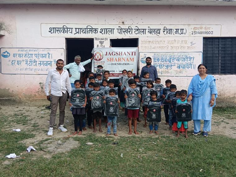 Children with their new school bags, volunteers and teachers outside the school, with the foundation banner (photo 1 of 10)