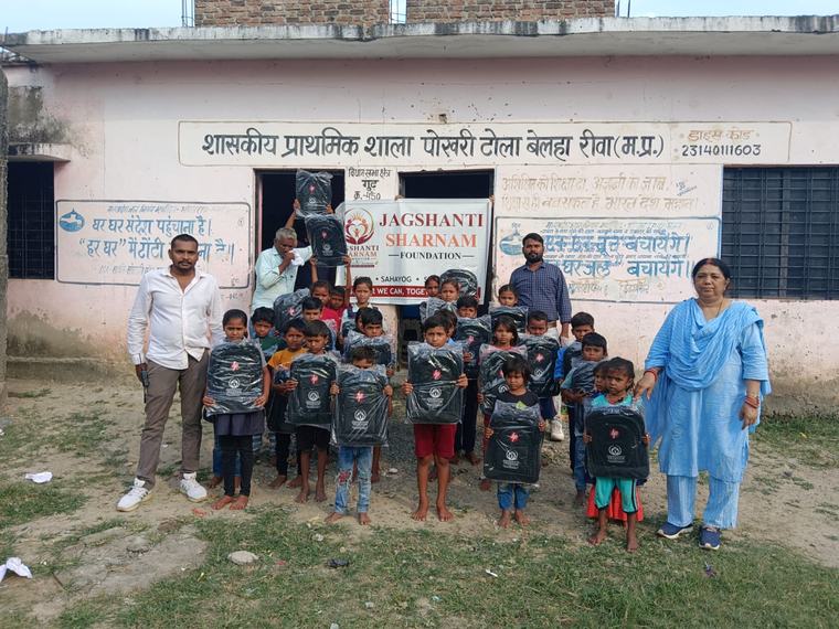 Children with their new school bags, volunteers and teachers outside the school, with the foundation banner (photo 4 of 10)